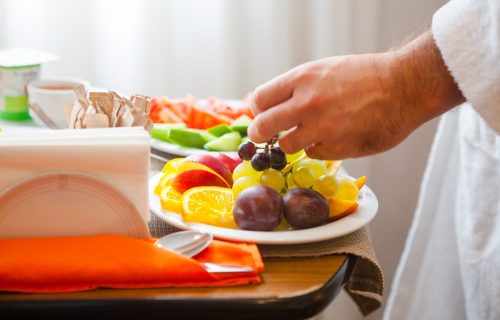 Close-up breakfast plate with fruit oranges, apple, grapes, plum, plate with tomato, cucumber